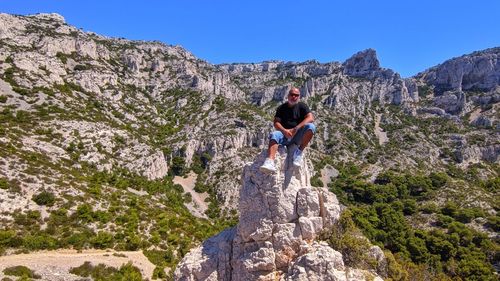 Full length of man on rock in mountains against sky