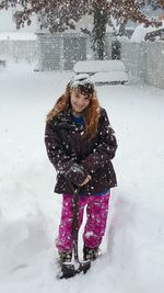 Portrait of smiling girl holding shovel during snowfall