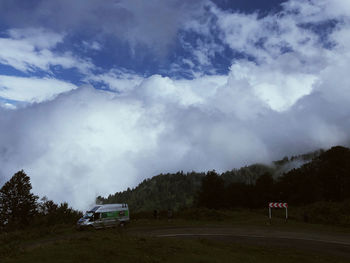 Road amidst trees on field against sky