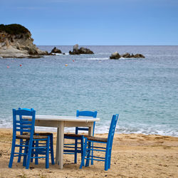 Chairs and tables on beach against clear blue sky