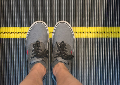 Low section of man standing on escalator