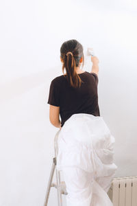 Side view of young woman sitting against white background