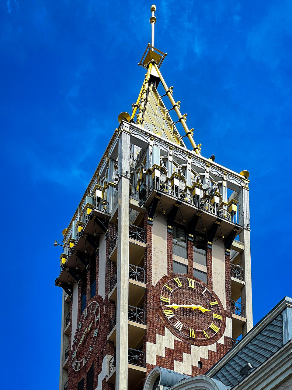 LOW ANGLE VIEW OF CLOCK TOWER AMIDST BUILDINGS AGAINST SKY