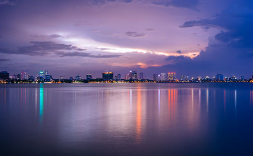 Scenic view of illuminated city buildings against sky during sunset