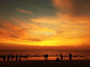 Silhouette people on beach against sky during sunset