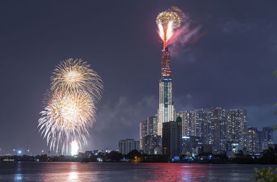 Firework display over illuminated buildings in city at night