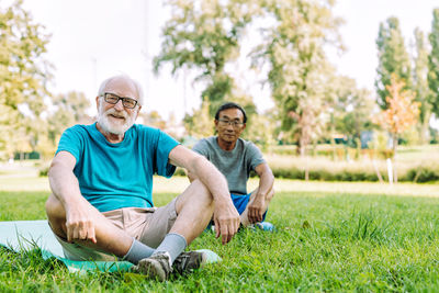 Friends sitting on grass against trees