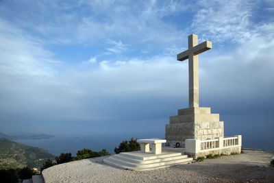 Cross by building against sky