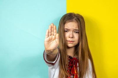 Portrait of young woman against blue background