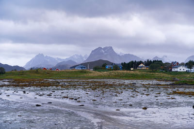 Scenic beach and  landscape with colorful houses and farm with mountains in lofoten norway