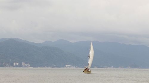 Sailboat in sea against mountains in the pacific ocean