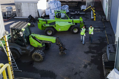 Engineers discussing by industrial machinery at recycling plant