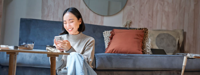 Portrait of young woman sitting on sofa at home