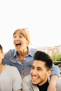 Mid adult woman laughing while standing by male friends at social gathering