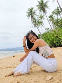 Young woman sitting on sand at beach