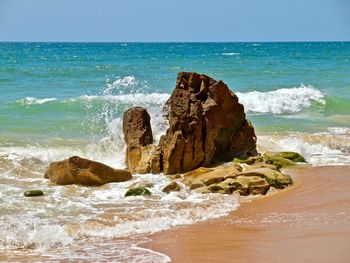 Scenic view of rocks on beach against sky