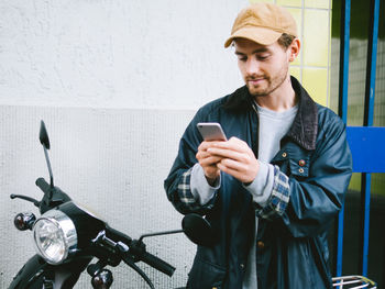 Young man using mobile phone by scooter