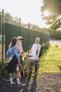 Senior women with bicycle talking to female friend on sunny day