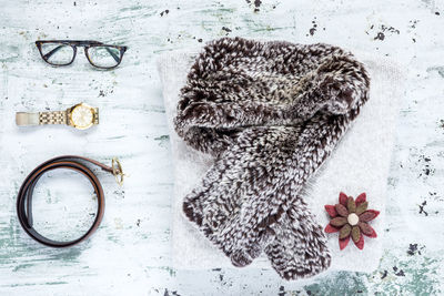 Directly above shot of scarf with personal accessories on wooden table