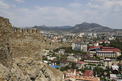 Aerial view of townscape by mountain against sky