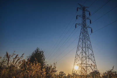 Electric pole and electric cable on the field in the countryside with blue sky.