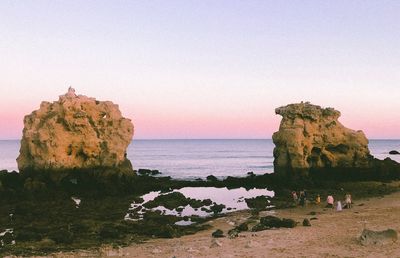 Rock formations on beach against clear sky