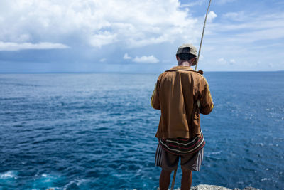 Rear view of man standing by sea
