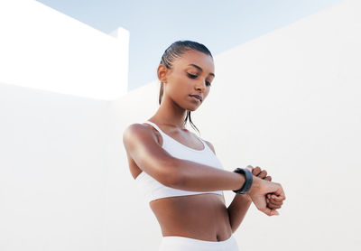 Portrait of young woman exercising against wall