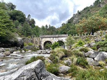 Arch bridge over rocks against sky