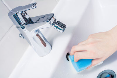 Close-up of person cleaning sink in bathroom