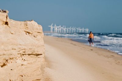 Man walking on beach against clear sky