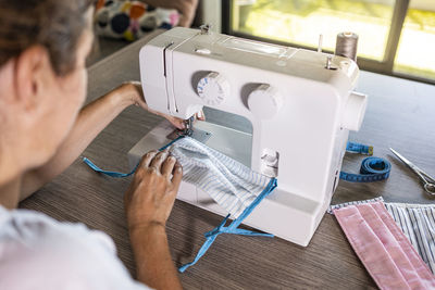 Woman making face masks with a sewing machine at home