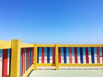 Multi colored railing at beach against clear blue sky