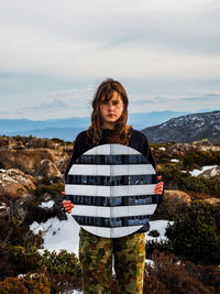 Portrait of young woman standing on mountain against sky