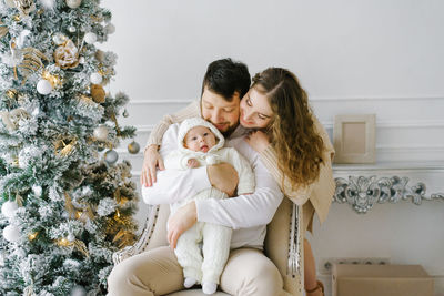 Happy young stylish family with a small child in a bright living room decorated for the new year.l