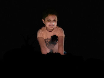 Portrait of man sitting against black background