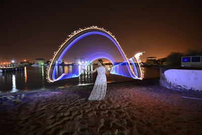 Illuminated ferris wheel in water at night