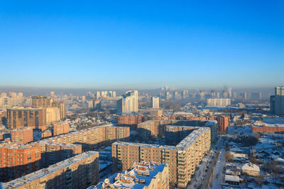 High angle view of buildings in city against clear blue sky