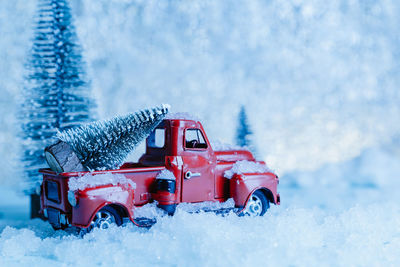 Red toy car on snow covered landscape during winter