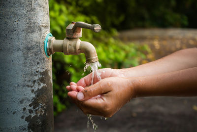 Cropped hands of child at drinking fountain