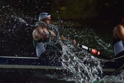 Sportsmen rowing boat in river