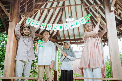 Portrait of smiling friends standing in greenhouse