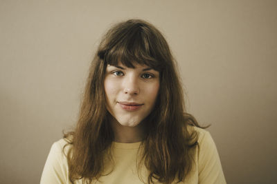 Close-up portrait of a young woman against wall