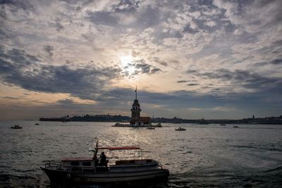 Boats in sea against cloudy sky