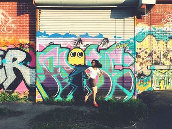 Full length of man standing against graffiti wall