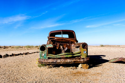 Abandoned vintage car on field against sky