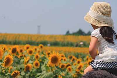 Man carrying daughter on shoulders at sunflower field