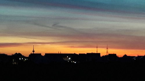 Silhouette of city against sky during sunset