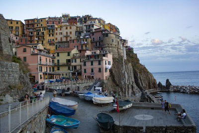 Boats moored on sea by buildings in city against sky
