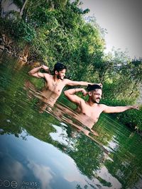 People enjoying in swimming pool against trees